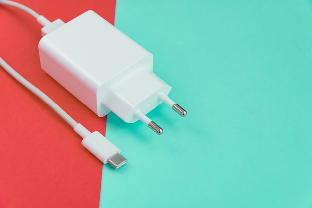 Oplader en USB-kabel type C over roze en blauwe achtergrond