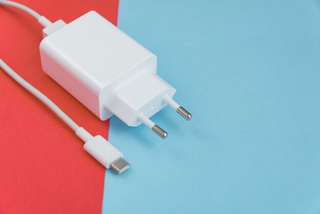 Oplader en USB-kabel type C over roze en blauwe achtergrond