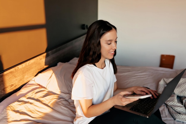 Opmerkelijke vrouw typt op laptop kantoormedewerker in wit overhemd geconcentreerd op het werk met laptop thuis op zonnige dag