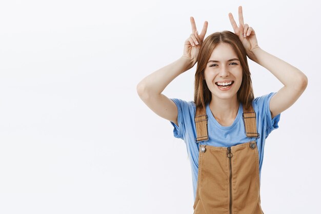 Optimistisch gelukkig aantrekkelijk meisje met vredesgebaar en lachen