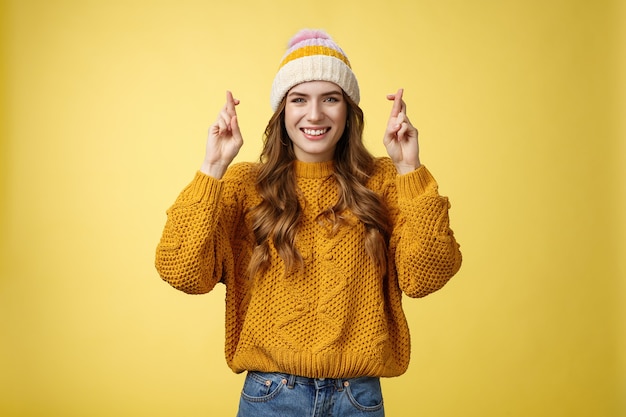 Optimistische gelukkige schattige jonge stijlvolle vrouwelijke universiteitsstudent bidden god help slagen voor examens kruis vinger...