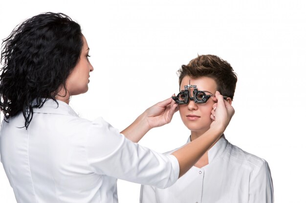 Optometrist die een bril van de oogtest houdt en aan jong vrouwenonderzoek geeft