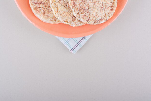 Oranje bord met heerlijke rijstwafels op witte tafel. Hoge kwaliteit foto