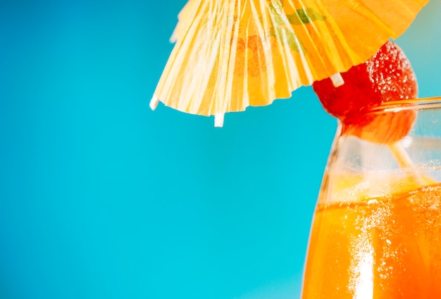 Oranje drankje met aardbei in paraplu versierd glas