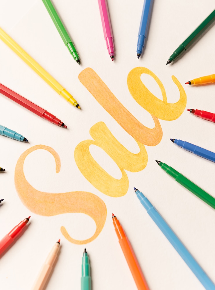 Gratis Foto oranje geschilderde belettering verkoop op witte achtergrond tussen markeringen