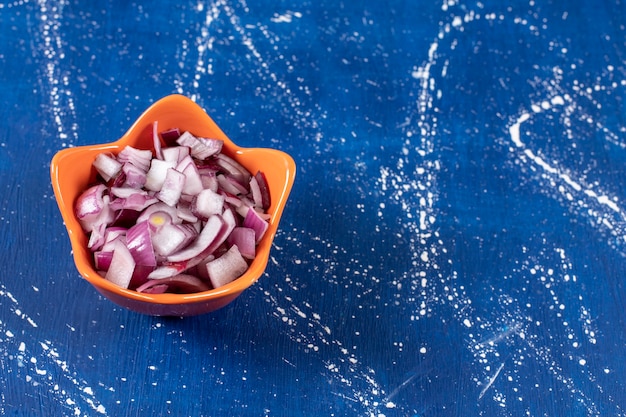 Gratis foto oranje kom gesneden paarse uien op marmeren tafel.