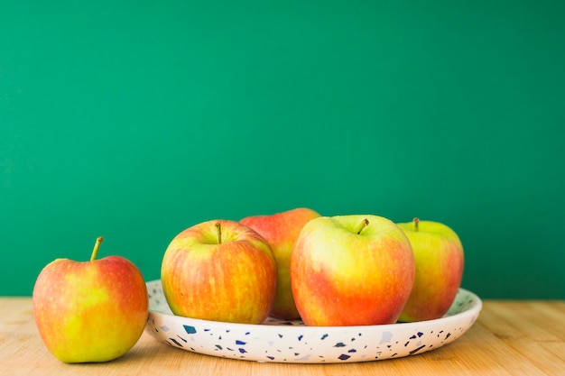 Organische appelen op plaat over de houten lijst tegen groene achtergrond