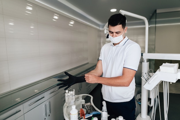 Orthodontist die chirurgische handschoenen in bureau zetten