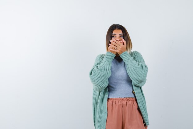 Ortrait die van vrouw handen op mond houdt in vrijetijdskleding en bang vooraanzicht kijkt