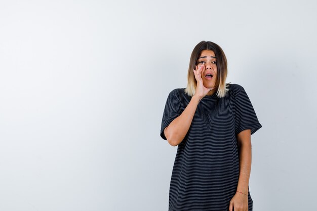 Ortrait van dame die geheim achter hand in zwart t-shirt vertelt en bezorgd vooraanzicht kijkt