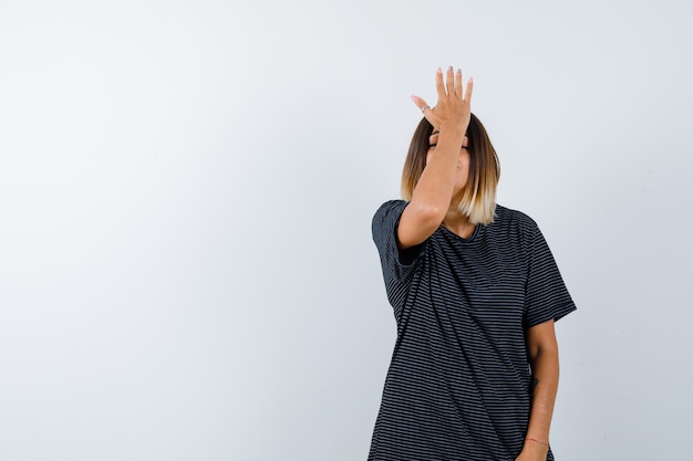 Ortrait van jong wijfje dat hand op voorhoofd in polokleding houdt en vergeetachtig vooraanzicht kijkt