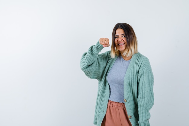 Ortrait van vrouw die met vuist in vrijetijdskleding dreigt en geamuseerd vooraanzicht kijkt