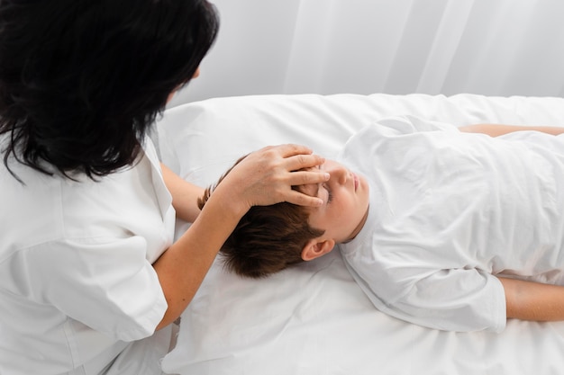 Osteopaat die een jongen behandelt door zijn hoofd te masseren