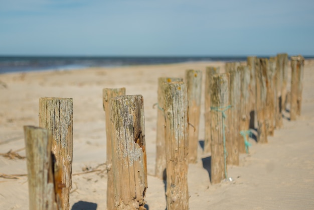 Oud ruw hout prikte in het zand en de zee in het wazige oppervlak