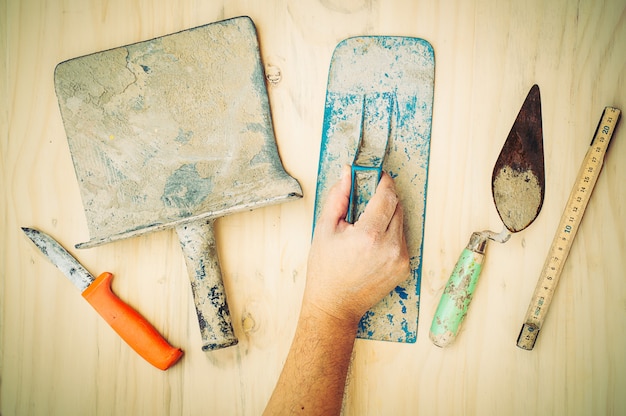 oude bouw handgereedschap met werknemer overhandigt witte houten achtergrond