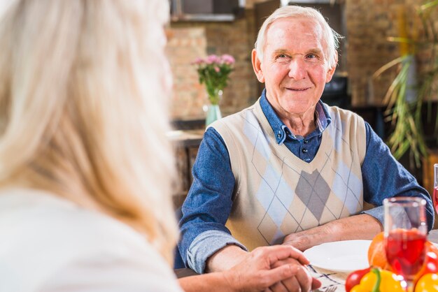 Oude lachende man zittend aan tafel