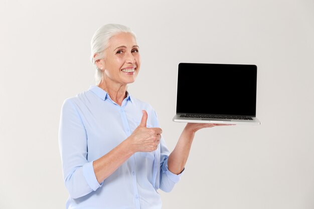 Oude laptop van de vrouwenholding en het tonen van omhoog geïsoleerde duim