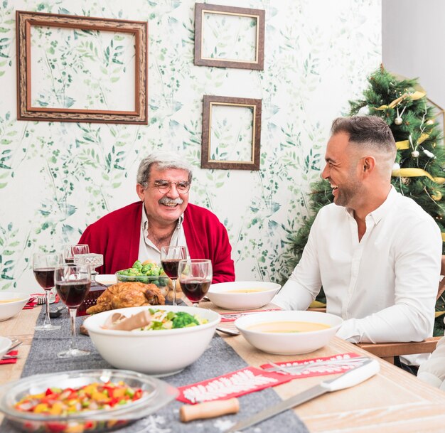 Oude man die aan zoon bij feestelijke lijst spreekt