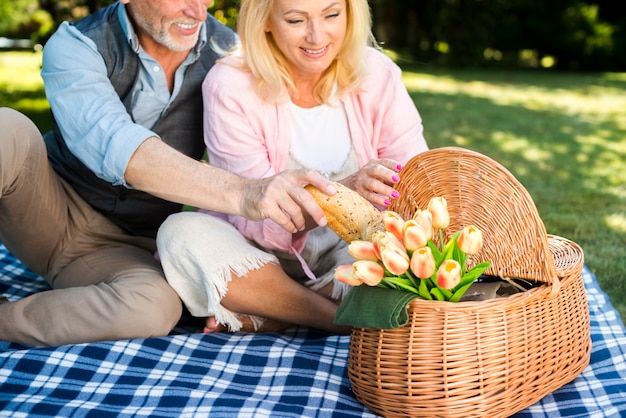 Oude man die brood van de picknickmand