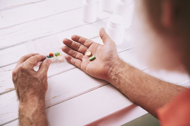 Oude man die pijnstillers neemt