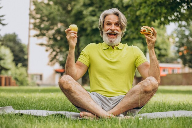 Oude man die tussen hamburger en appel kiest