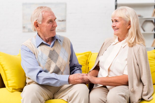 Oude man en vrouw die op gele bank spreken