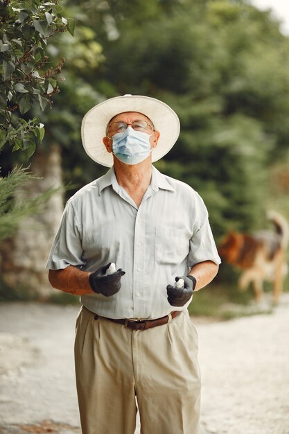 Oude man in een medisch masker. Man in het park. Coronavirus-thema.