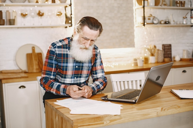 Oude man met laptop. Grootvader zit in een kerstversiering.