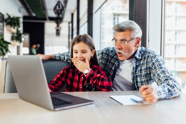 Oude man met zijn kleindochter die een tablet gebruikt om een videogesprek met het kind te voeren.