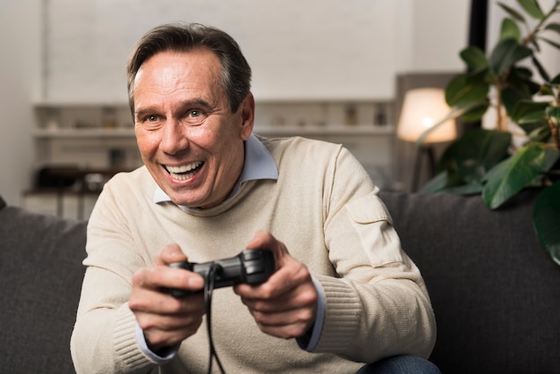 Oude mens die en videospelletje glimlacht speelt