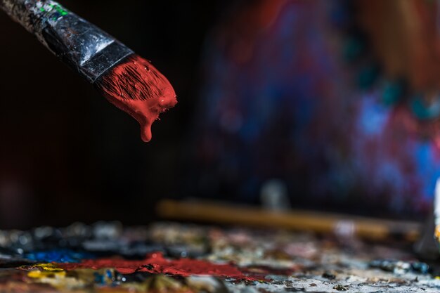 Oude penseel onderdompelen in rode kleur