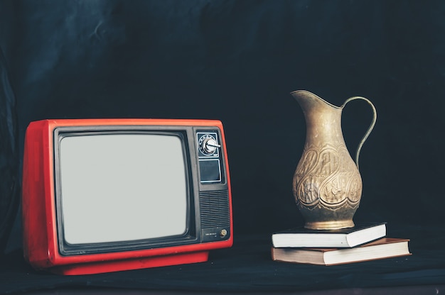 Gratis foto oude retro tv door bloemenvazen op boeken te plaatsen