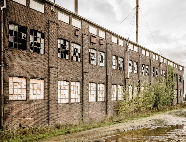 Oude verlaten stenen gebouw met gebroken ramen en een plas buiten