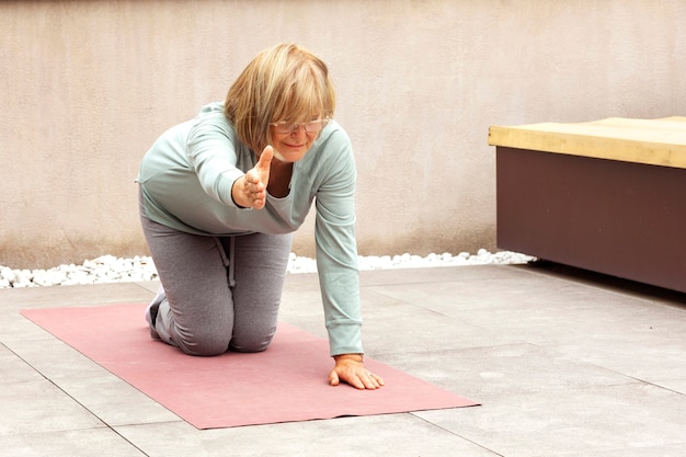 Gratis foto oude vrouw die fitnessoefeningen doet