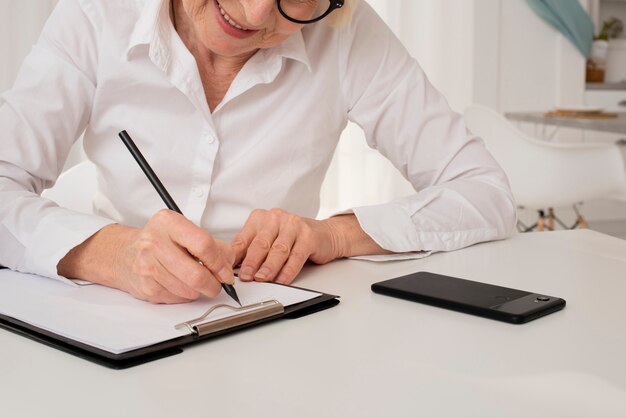 Oude vrouw die op een klembord schrijft