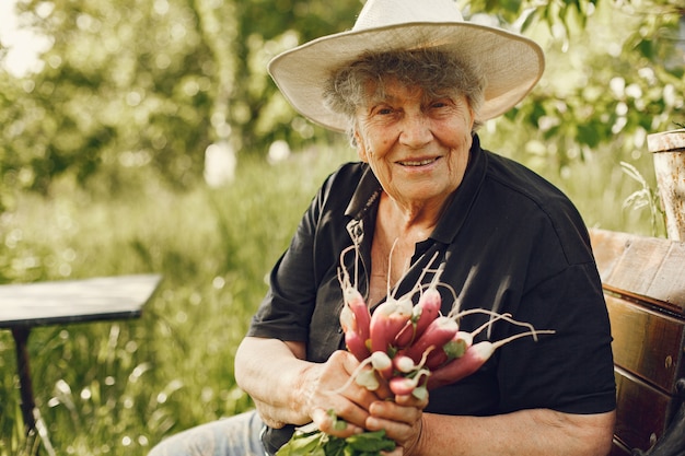 Oude vrouw in een hoed met verse radijs