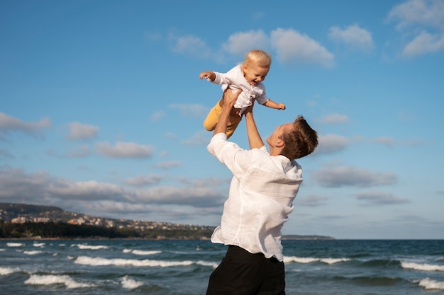 Gratis foto ouder met baby op het strand bij zonsondergang