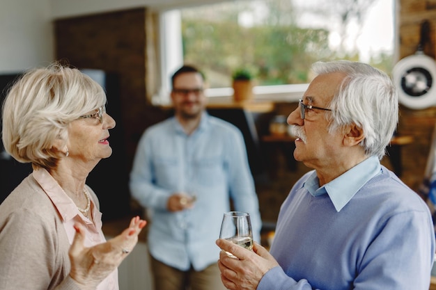 Ouder stel in gesprek in de keuken Hun volwassen zoon staat op de achtergrond