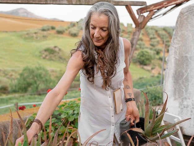 Gratis foto oudere boerin die haar planten water geeft