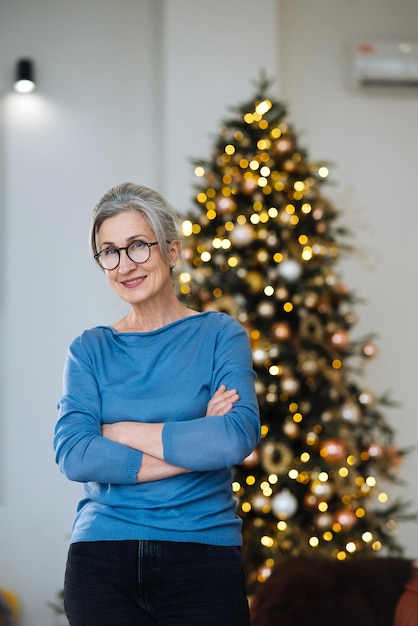 Oudere dame lacht en kijkt in de camera kerstboom op de achtergrond