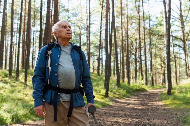 Oudere man die de natuur met rugzak onderzoekt