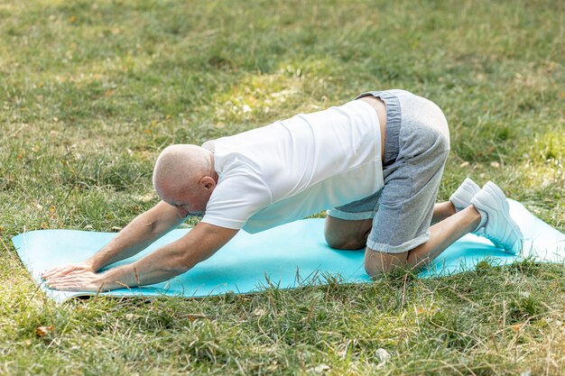 Oudere man doet yoga buitenshuis