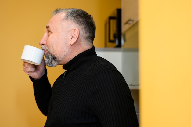 Gratis foto oudere man drinken uit een kopje koffie