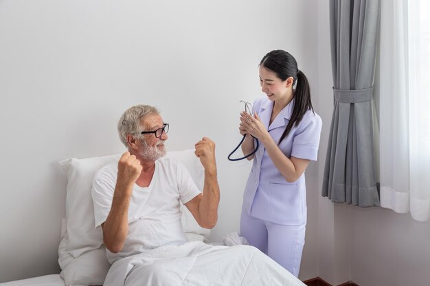 Oudere man gezonde opkomst vuist omhoog met gelukkige verpleegster in slaapkamer bij verpleeghuis duim omhoog