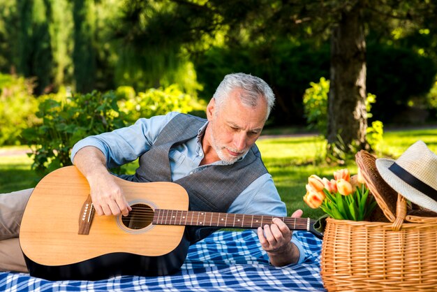 Oudere man gitaarspelen op de picknick