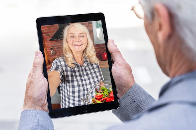 Oudere man in de stad die tablet gebruikt voor videogesprek