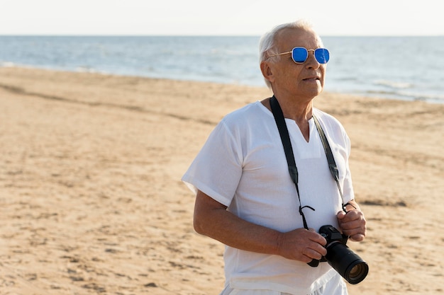 Oudere man met camera aan het strand