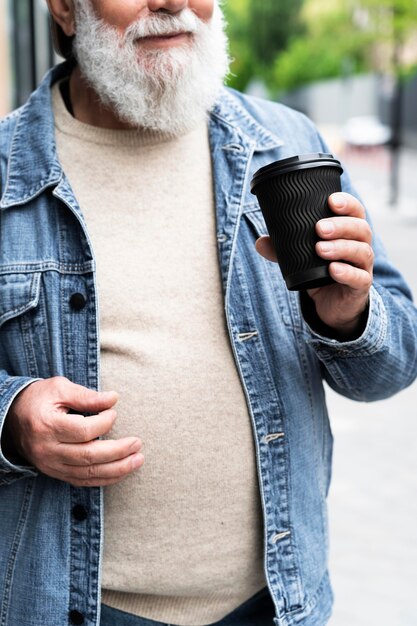 Oudere man met een kopje koffie buiten in de stad