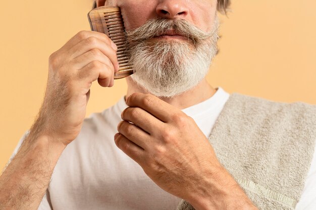 Oudere man met handdoek kammen van zijn baard