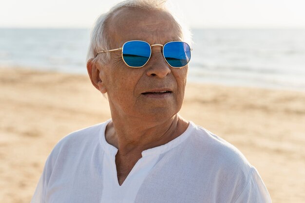 Oudere man met zonnebril genieten van zijn tijd op het strand